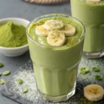 Thick banana matcha smoothie topped with banana slices and matcha powder