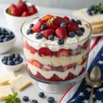 Layered berry trifle in glass bowl with strawberries and blueberries for July 4th