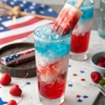 Layered red, white, and blue Bomb Pop cocktail with strawberries and blueberries.