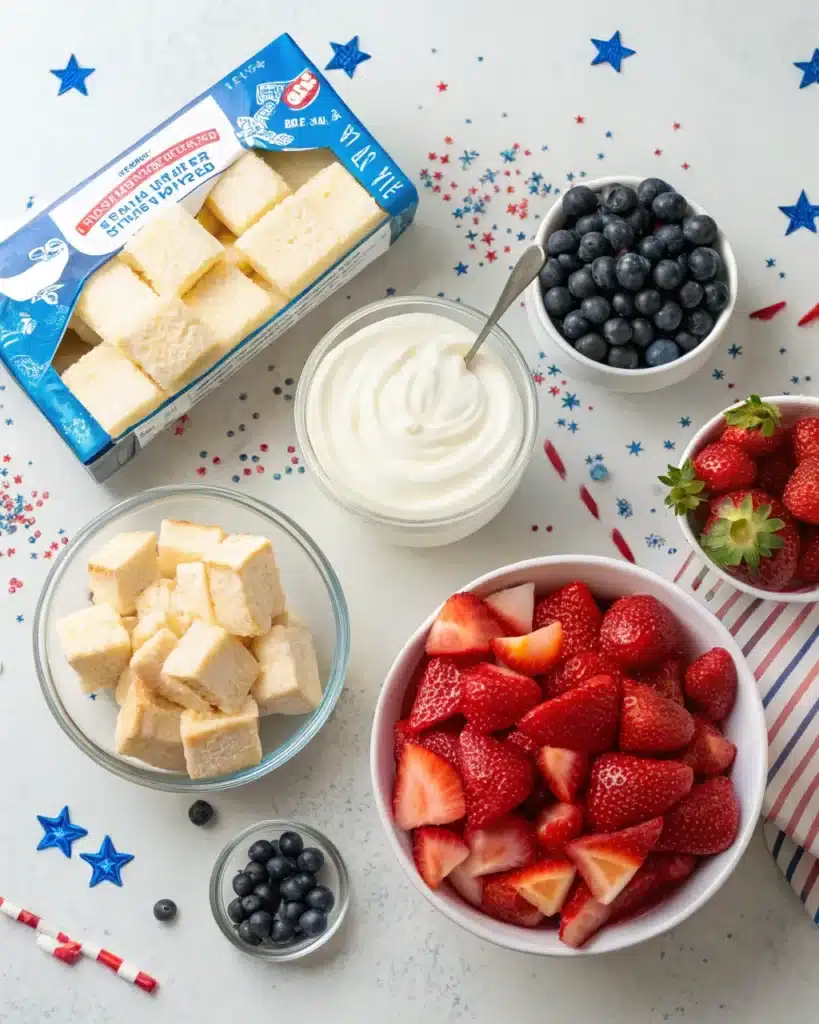 Ingredients for 4th of July trifle including strawberries, blueberries, cake cubes, and whipped topping
