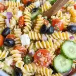 Tri-color rotini pasta salad with cucumbers, olives, tomatoes, and feta