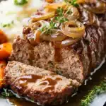 Meatloaf with caramelized onions and gravy next to mashed potatoes