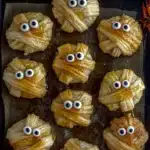 Golden round baked cheese mummies with puff pastry strips and spooky eyes.