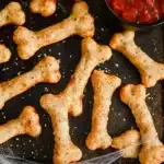 Bone-shaped cheesy Halloween breadsticks with marinara dipping sauce.