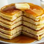 Buttermilk pancakes cut to show fluffy texture, topped with butter and syrup