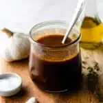 Jar of homemade balsamic vinaigrette with garlic, olive oil, and herbs