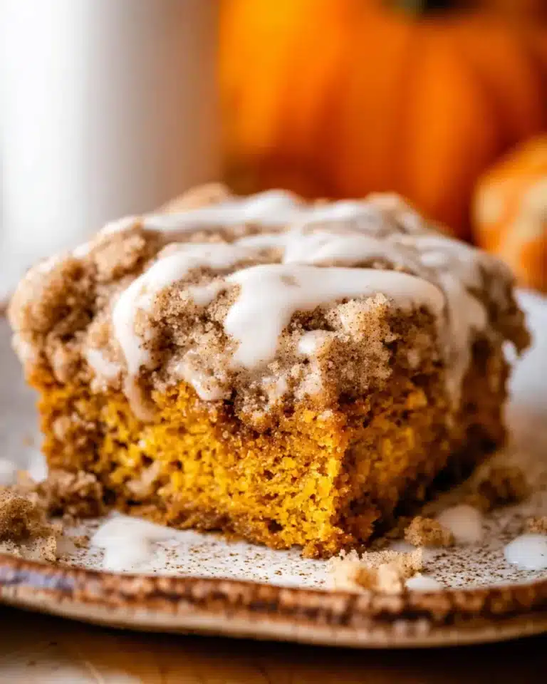 Moist pumpkin coffee cake slice with cinnamon streusel and vanilla icing drizzle