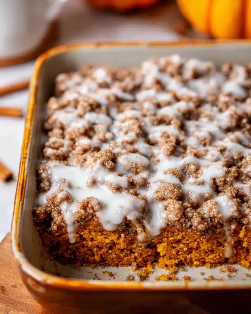 Freshly baked pumpkin coffee cake with cinnamon streusel and icing in a pan