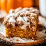 Close-up of pumpkin coffee cake slice with streusel and glaze on ceramic plate