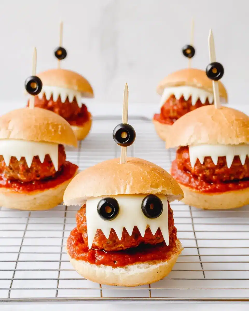 Monster meatball sliders with mozzarella teeth and olive eyes on a cooling rack