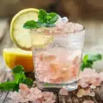 Sparkling pink salt drink with lemon and mint on rustic wood