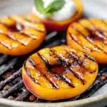 Caramelized peaches on grill topped with cream and mint for a summer dessert.