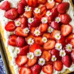 Decorated strawberry shortcake with flower garnish on sheet pan
