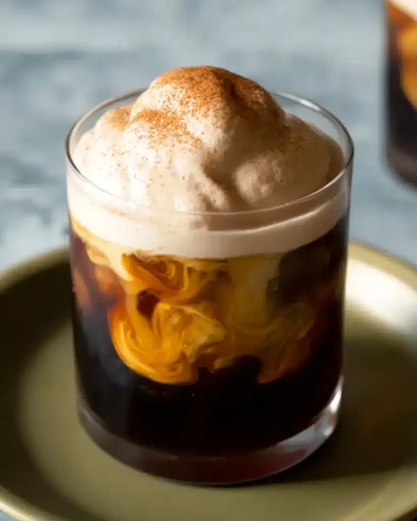Iced coffee topped with fluffy pumpkin spice cold foam and cinnamon