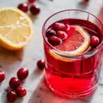 Glass of cranberry juice with lemon slice and fresh cranberries