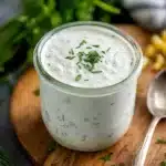 Glass jar of homemade ranch dressing with parsley and dill