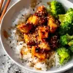 Crispy orange salmon with sesame seeds over rice and broccoli