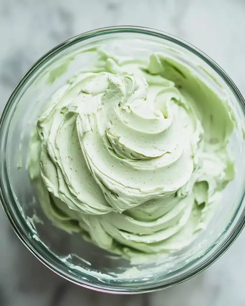 Swirled pistachio buttercream frosting in glass bowl