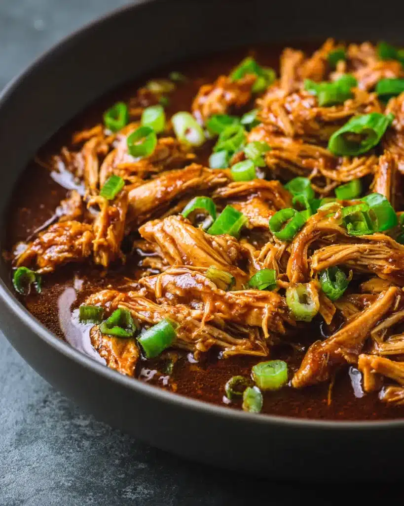Crock Pot bourbon chicken simmering in slow cooker with sauce