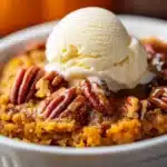 Pumpkin pecan cobbler in ramekin topped with ice cream and caramel drizzle