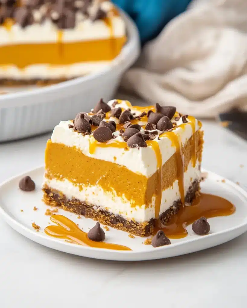 Layered pumpkin lush with whipped topping, caramel, and chocolate chips on a plate