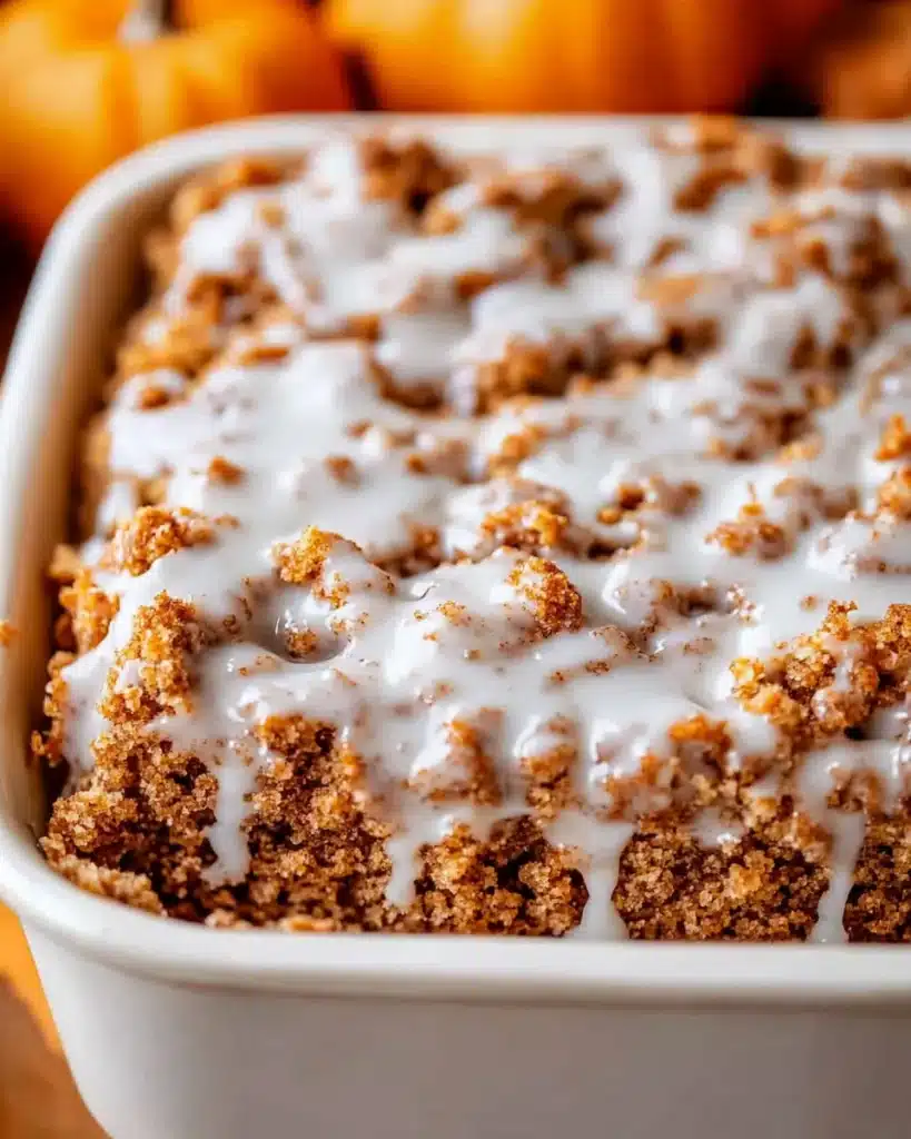 Baked pumpkin streusel coffee cake in white dish with glaze