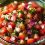 Chunky pico de gallo salsa with tomatoes, onion, and cilantro in glass bowl