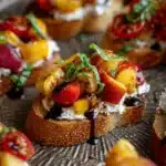 Close-up of peach bruschetta with ricotta, tomatoes, basil, and balsamic glaze on crispy bread.
