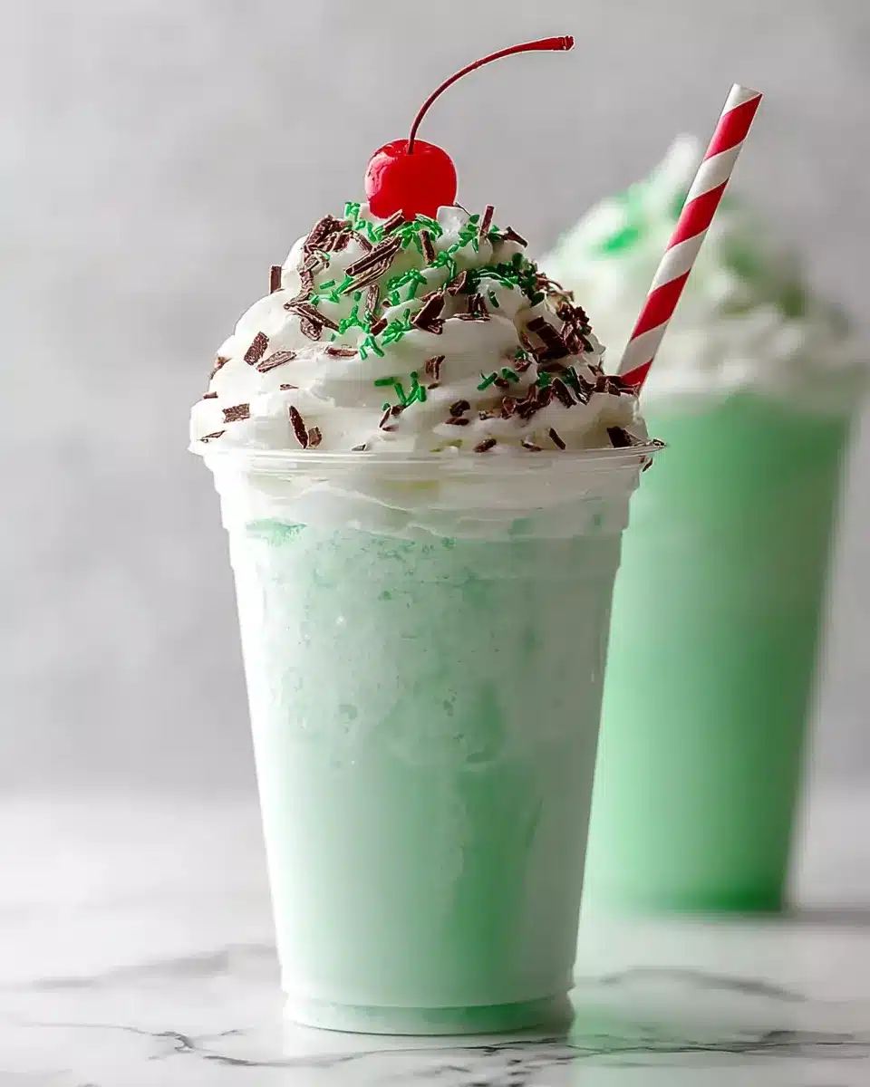 Mint green homemade Shamrock Shake topped with whipped cream, sprinkles, and a cherry.