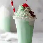 Festive green Shamrock Shake with whipped cream, cherry, and sprinkles.