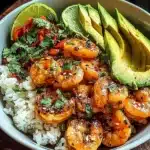 Spicy shrimp bowl with avocado slices, lime, rice, and herbs