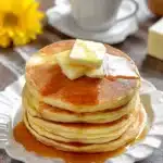 Fluffy Bisquick pancakes with butter, syrup, and coffee in background
