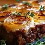 French onion meatloaf with caramelized onion spirals, melted cheese, and fresh thyme sprigs.