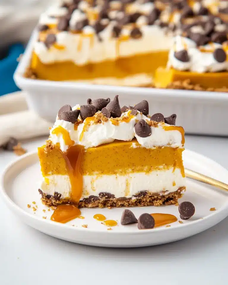 Slice of pumpkin lush dessert with graham crust, whipped cream, caramel, and chocolate chips