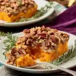 Sweet potato casserole with pecan topping served on white plate
