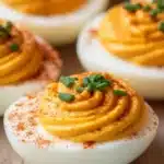 Spicy pumpkin deviled eggs topped with paprika and chives