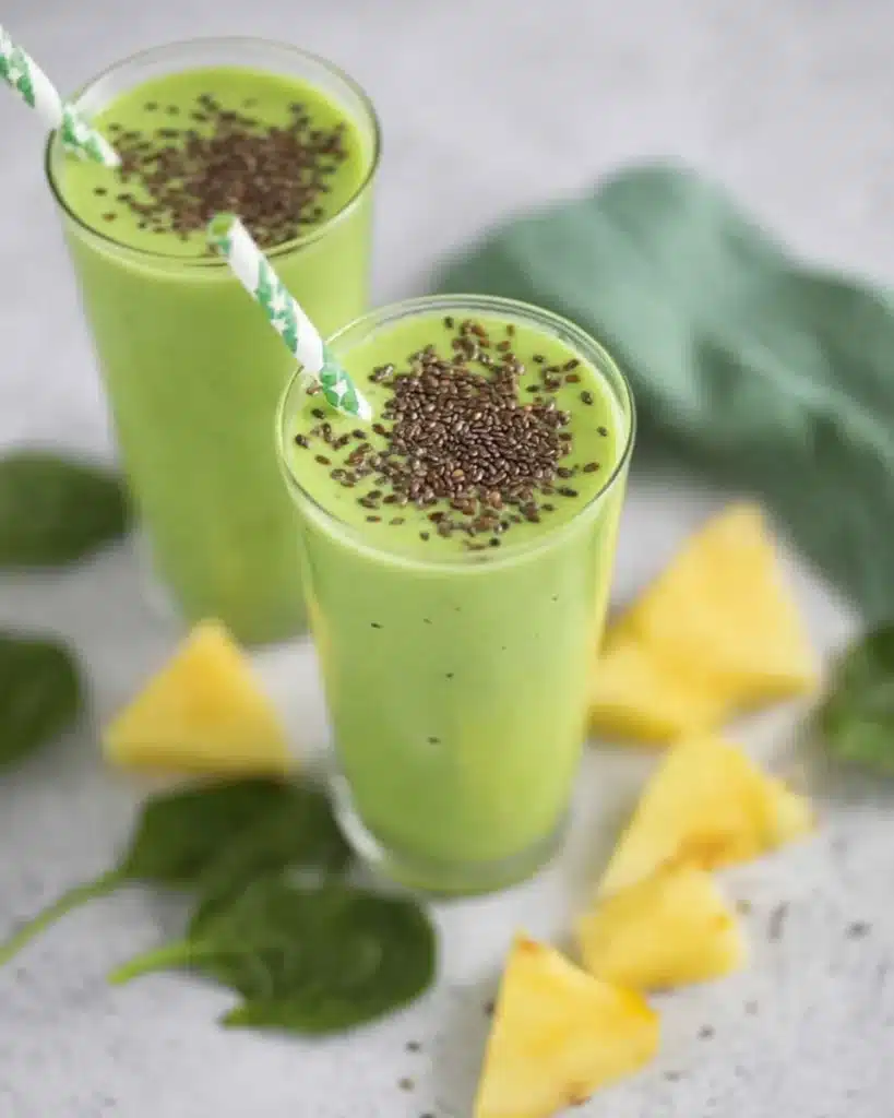 Healthy green smoothies with pineapple chunks and spinach leaves