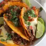 Slow cooker birria tacos with shredded beef, crispy tortillas, and dipping consommé