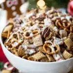 Gingerbread Chex Mix with pretzels and white chocolate drizzle in a holiday bowl.