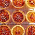 Glossy candied blood orange slices drying on a wire rack