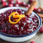 Homemade cranberry sauce with orange peel and cinnamon in a white bowl